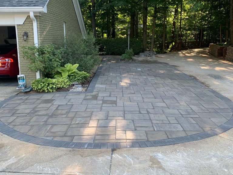 Curved charcoal paver driveway extension with integrated lamp post planter cutout and brick border in Cicero, Indiana