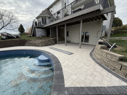 Paver patio with integrated drainage system installed alongside residential pool in Fort Dodge, Iowa