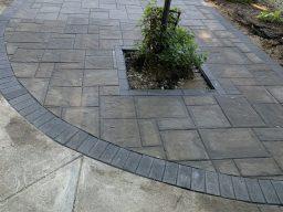 Curved charcoal paver driveway extension with integrated lamp post planter cutout and brick border in Cicero, Indiana