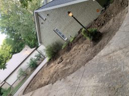 Curved charcoal paver driveway extension with integrated lamp post planter cutout and brick border in Cicero, Indiana