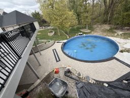 Paver patio with integrated drainage system installed alongside residential pool in Fort Dodge, Iowa